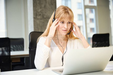 Téléchargez les photos : Femme épuisée faire des appels de vente e-commerce à l'aide d'un ordinateur portable au bureau - en image libre de droit