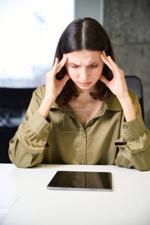 Téléchargez les photos : Femme d'affaires malade fatiguée travaillant avec tablette et souffrant de maux de tête dans le bureau de l'entreprise - en image libre de droit