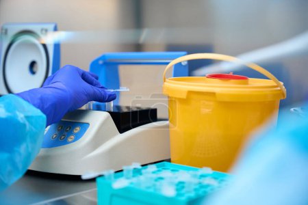 Téléchargez les photos : L'assistant de laboratoire analyse les biomatériaux dans une pièce stérile à l'aide de gadgets de laboratoire spéciaux - en image libre de droit
