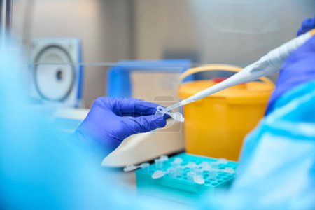 Téléchargez les photos : Un employé de laboratoire analyse les biomatériaux dans une pièce stérile à l'aide de gadgets de laboratoire spéciaux - en image libre de droit