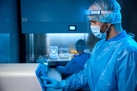 Médico virólogo trabaja en equipos especiales para estudiar biomaterial, la esterilidad se mantiene en el laboratorio