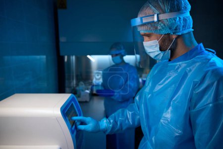 Téléchargez les photos : L'homme travaille sur un équipement spécial pour la recherche de biomatériaux, les gens utilisent des accessoires de protection - en image libre de droit