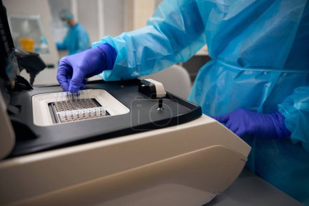 Técnico de laboratorio virólogo utiliza un aparato especial para estudiar biomaterial, la gente trabaja en guantes de protección