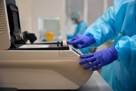 Téléchargez les photos : Technicien de laboratoire utilise un appareil spécial pour étudier les biomatériaux, les gens travaillent dans des gants de protection - en image libre de droit