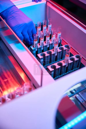 Especialista trabaja con muestras etiquetadas de biomaterial en un laboratorio moderno utilizando equipos de alta tecnología