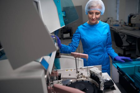 Inmunólogo femenino utiliza una máquina para el aislamiento automático de ácidos nucleicos, equipos modernos en el laboratorio