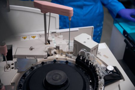Foto de Inmunólogo asistente de laboratorio utiliza un dispositivo para el aislamiento automático de ácidos nucleicos, equipos modernos en el laboratorio - Imagen libre de derechos