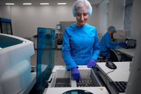 Asistente de laboratorio trabaja con muestras de sangre en el laboratorio, utilizando una máquina para la extracción automática de ácidos nucleicos