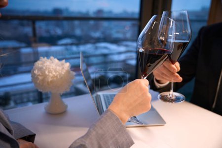 Téléchargez les photos : Les gens boivent du vin dans un restaurant, il ya un ordinateur portable sur la table à côté d'eux - en image libre de droit