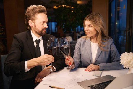 Foto de Hombre y una mujer se comunican en un acogedor restaurante, hay vino tinto en vasos - Imagen libre de derechos
