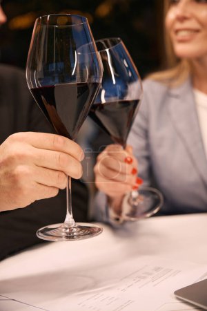 Foto de Mujer y hombre se comunican a través de una copa de vino tinto, la mujer tiene una manicura ordenada - Imagen libre de derechos