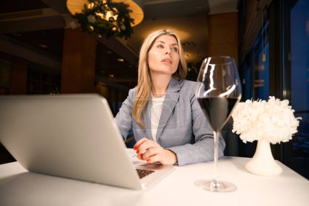 Foto de Mujer solitaria está trabajando con documentos en una sala de restaurante, ella está en un elegante traje de negocios - Imagen libre de derechos
