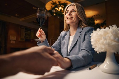 Foto de Mujer de negocios sonriente con una copa de vino tinto, un hombre sentado enfrente - Imagen libre de derechos