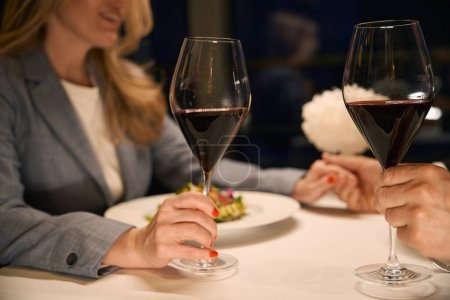 Photo for Couple at dinner tenderly holds hands, there is a light dinner and wine on the table - Royalty Free Image