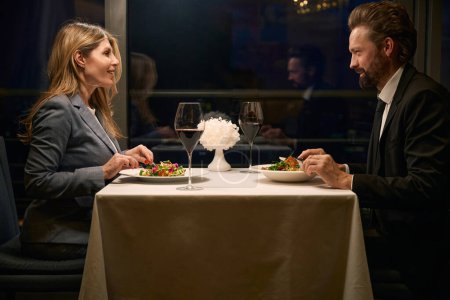 Foto de Hombre y una mujer se comunican durante la cena en un restaurante acogedor, vino tinto se ordena - Imagen libre de derechos