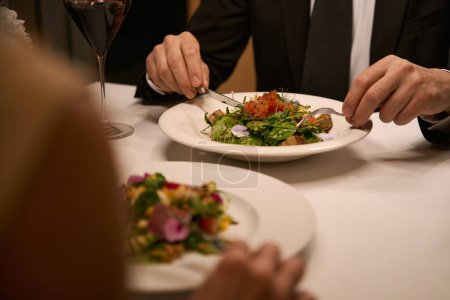 Foto de Pareja cenando en un acogedor restaurante, ensalada ligera servida - Imagen libre de derechos