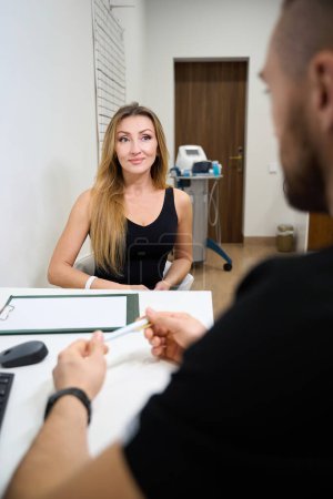 Téléchargez les photos : Belle femme à un rendez-vous de physiothérapeute, les gens communiquent dans une pièce lumineuse - en image libre de droit