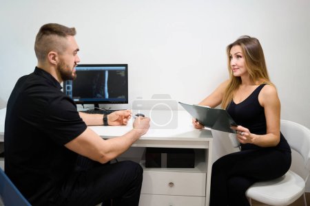 Foto de Paciente en una cita con un fisioterapeuta, una mujer completa un cuestionario - Imagen libre de derechos
