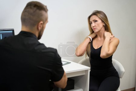 Photo for Patient consulting with a physiotherapist in a rehabilitation center, a woman complains of back pain - Royalty Free Image