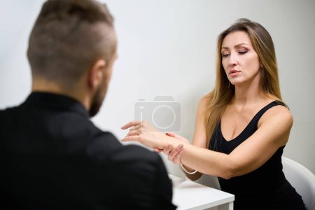 Photo for Patient is consulting with a doctor physiotherapist in a rehabilitation center, a woman complains of pain in her arm - Royalty Free Image