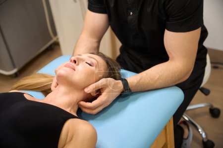 Sesión de terapia manual en un centro de bienestar, un especialista masajea el cuello de una mujer