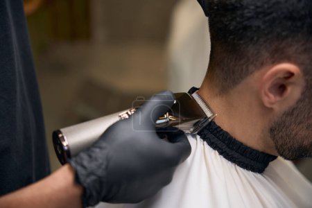 Téléchargez les photos : Coiffeur homme faisant coupe de cheveux pour le client au salon de coiffure - en image libre de droit