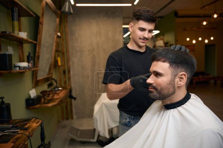 Téléchargez les photos : Coiffeur professionnel coupe coiffure pour client par tondeuse à cheveux dans le salon de coiffure - en image libre de droit