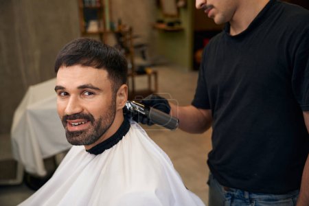 Foto de Peluquero con cortador de pelo para hacer corte de pelo elegante para el cliente en la barbería - Imagen libre de derechos