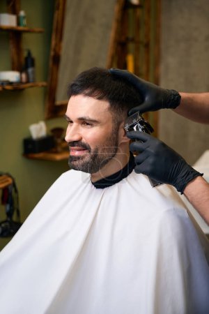 Foto de Peluquero con cortador de pelo para hacer corte de pelo elegante para el cliente en la barbería - Imagen libre de derechos