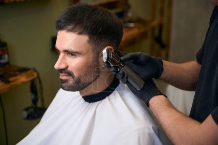 Foto de Peluquería con cortapelos para hacer un corte de pelo elegante para el cliente en la barbería - Imagen libre de derechos