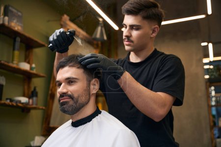 Téléchargez les photos : Coiffeur professionnel utilisant de la poudre de talc pour ses cheveux de client au salon de coiffure - en image libre de droit