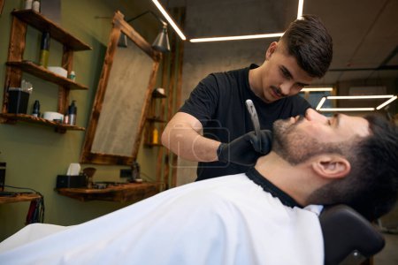 Téléchargez les photos : Barbier parures mans barbe dans le salon de coiffure professionnel - en image libre de droit