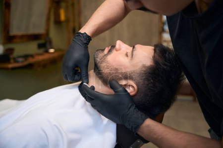 Foto de Barbudo hombre conseguir afeitado con afeitadora de borde recto por peluquería en la barbería - Imagen libre de derechos