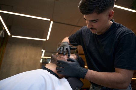 Téléchargez les photos : Homme client visitant salon de coiffure pour le style et le toilettage de sa barbe - en image libre de droit