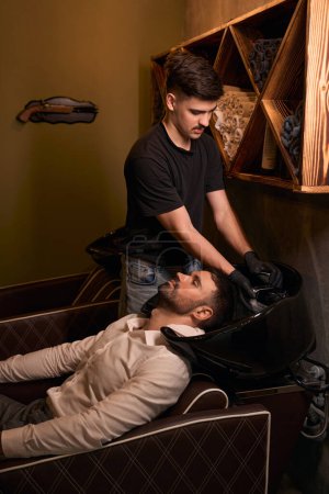 Téléchargez les photos : Coiffeur laver les cheveux clients dans le salon de coiffure professionnel - en image libre de droit