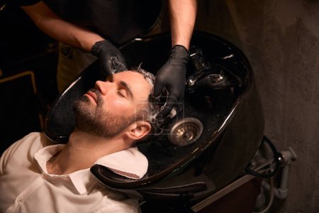 Téléchargez les photos : Jeune homme qui aime se laver les cheveux au salon de beauté ou au salon de coiffure - en image libre de droit