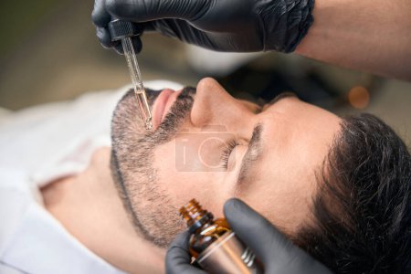 Foto de Aceite para barba en el proceso de gotero de hidratación del cabello para el cliente en la barbería - Imagen libre de derechos