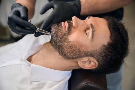 Téléchargez les photos : Style barbe et coupe avec ciseaux pour homme client au salon de coiffure - en image libre de droit