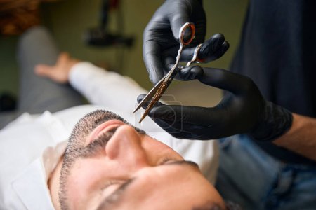 Téléchargez les photos : Homme barbu se faire couper les cheveux de barbe par coiffeur au salon de coiffure - en image libre de droit