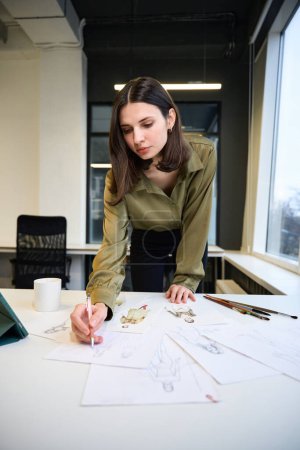 Photo for Professional clothing designer drawing sketches in her office - Royalty Free Image