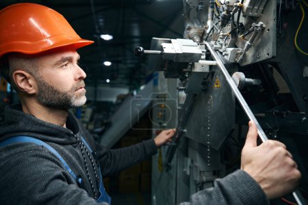 Employee uses high-tech equipment to cut a spacer frame, a man in a safety helmet