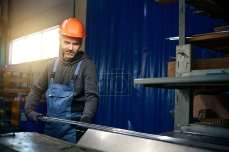 Arbeiter benutzt modernes Gerät in einer Fensterproduktion, ein Mann mit orangefarbenem Hut