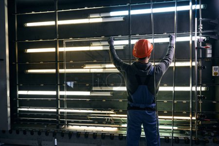 Foto de Master realiza el prensado de una ventana de doble acristalamiento en la producción de una ventana, un hombre con un casco naranja - Imagen libre de derechos