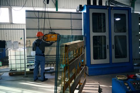 Foto de Trabajador en un taller de producción de ventanas utiliza un dispositivo de montaje y elevación al vacío - Imagen libre de derechos
