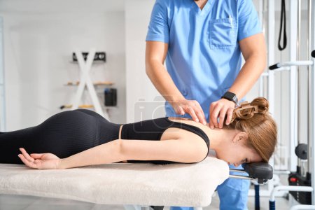 Téléchargez les photos : Massothérapeute travaille avec les vertèbres cervicales d'une jeune femme, une femme s'allonge sur le ventre sur une table de massage - en image libre de droit