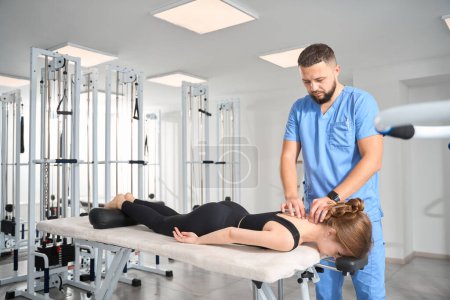 Chiropraktiker-Massagetherapeutin arbeitet mit den Halswirbeln junger Frauen, Frau liegt auf dem Bauch auf Massagetisch