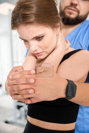 Téléchargez les photos : Chiropraticien en uniforme bleu aligne la colonne vertébrale d'une patiente, une femme s'assoit sur une table de massage - en image libre de droit