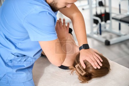 Frau liegt auf Massagetisch, Osteopath arbeitet an der Wirbelsäule