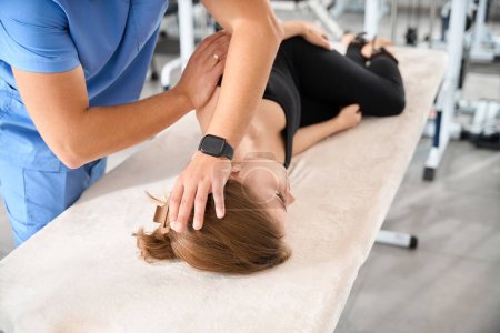 Téléchargez les photos : Jeune femme couchée sur une table de massage, un ostéopathe travaille sur son cou - en image libre de droit