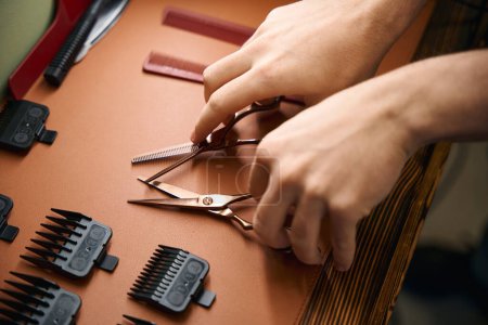 Téléchargez les photos : Ciseaux de coupe de cheveux professionnels dans les mains de coiffeur méconnaissables dans le salon de coiffure - en image libre de droit